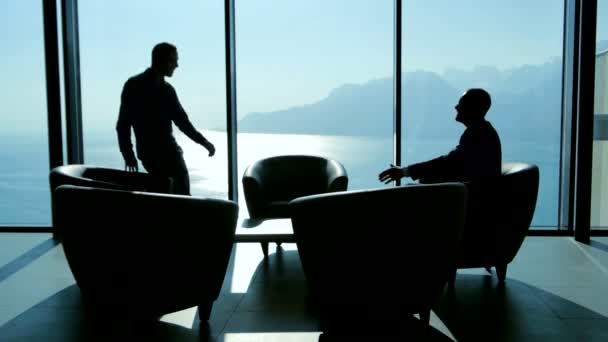Silhouetten van twee zakenlieden handshaking en praten — Stockvideo