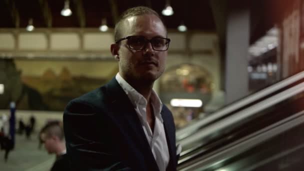 Geschäftsmann mit Brille erklimmt Rolltreppe — Stockvideo
