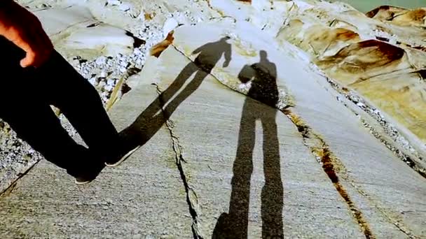 Shadow of two male hikers walking on stone rock — Stock Video