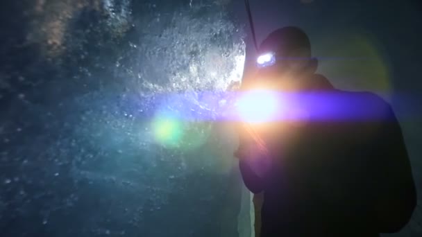 Ученый исследует ледниковую пещеру с фонариком — стоковое видео