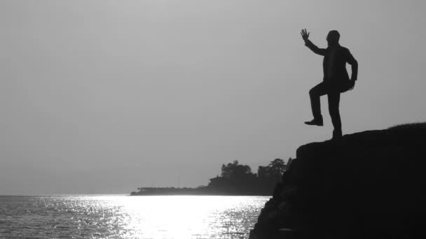 Silhueta de um homem fazendo exercícios ao pôr do sol — Vídeo de Stock