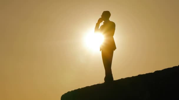 Silhouette di un uomo che parla al cellulare al tramonto — Video Stock