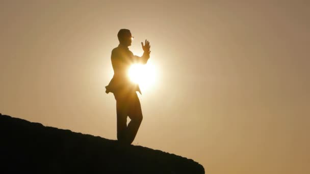 Silhouet van een man doen oefeningen bij zonsondergang — Stockvideo