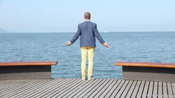 Человек, поднимающий руки, стоя на деревянной платформе — стоковое видео