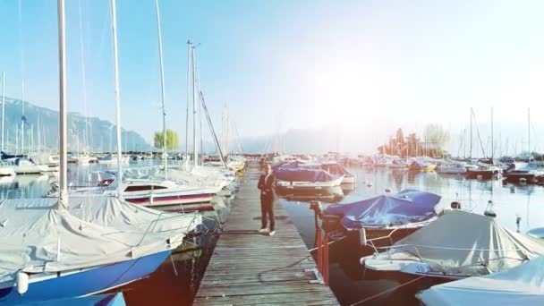 Young businessman standing among the yachts and boats in the marina — Stock Video