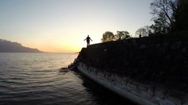 Adam silah göl kıyısında günbatımı içinde yetiştirme