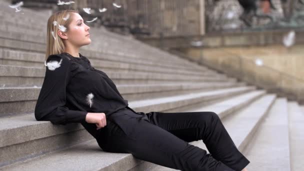 Mujer rubia sentada en las escaleras con plumas de luz — Vídeos de Stock