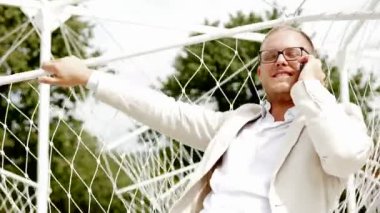 Adam salıncak üzerinde cep telefonuyla konuşuyor