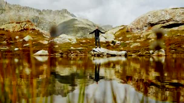 El hombre está de pie frente al lago de montaña — Vídeo de stock