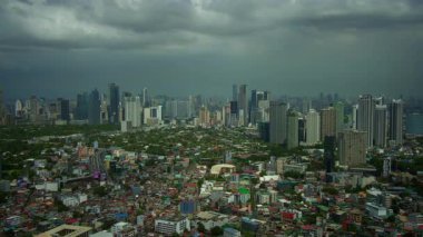 Modern gökdelenlerin ve karamsar gökyüzünün altında renkli mahallelerin yer aldığı canlı bir şehir manzarası..