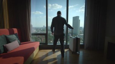 Bir gezgin şık bir otel odasından şehrin siluetine hayran kalır, rahatlama, macera ve merak ile birleşir.
