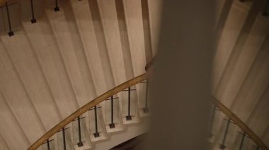 Yalnız Asyalı kadın lobide lobide sinematik mermer sarmal merdiven çıkıyor.