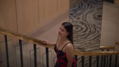 Merdiven boşluğunda dinlenen düşünceli bir kadın, merdiven üzerinde düşünceli bir şekilde duran bir kadın.