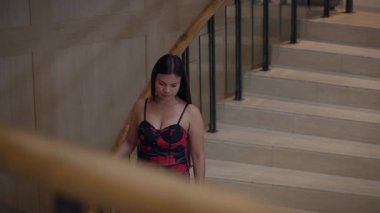 Zarif bir kadın mermer merdivenlerden iniyor, zarif bir şekilde mermer merdivenlerden aşağı yürüyor.