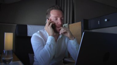 Bir iş adamı, bir telefon görüşmesi sırasında dizüstü bilgisayarıyla modern uzaktan çalışmanın dinamiklerini vurguluyor.