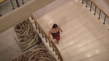 Kadın zarif bir şekilde mermer merdiveni tırmanıyor, Asyalı kadın zarif bir şekilde mermer merdivenlerden çıkıyor.