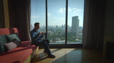 Şık bir daireden güzel bir şehrin ufuk çizgisine bakarken hayatı düşünen düşünceli bir insan.