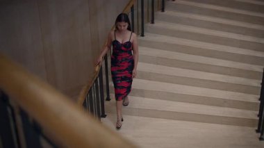 Zarif kadın merdivenlerden iniyor, kırmızılı tek başına kadın mermer merdivenlerden dikkatlice iniyor. Altınla.