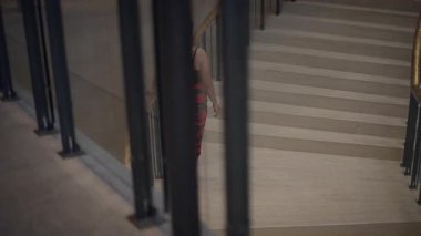 woman navigates stairs, modern atrium features woman weaving through staircase columns in vibrant