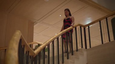 asian influencer pauses on marble stairs, stylish influencer resting on marble staircase in warm
