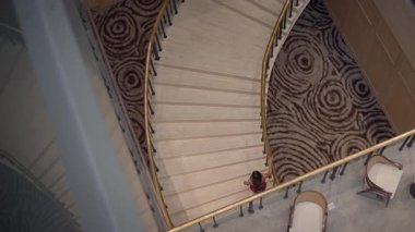 intimate hotel interior featuring asian visitor on elegant curved staircase with luxurious details
