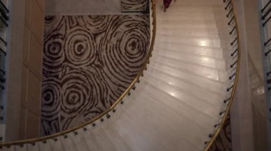 contemplative moment captured over curved staircase and striking carpet in quiet hotel corridor
