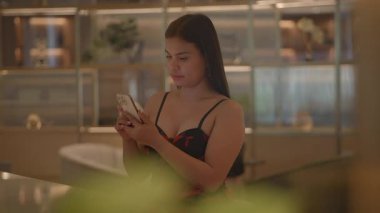 young woman relaxing with phone, relaxed young woman in floral dress browsing phone amidst plants