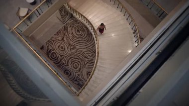 overhead view emphasizes elegant marble staircase and plush patterned carpet during evening checkin