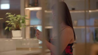 customer enjoying her time at cafe counter, woman leisurely explores and relaxes inside cozy cafe