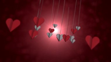 yumuşak bokeh arka planda asılı kırmızı kalpler, ince teller ve nazik salınımlar sıcak oluşturur