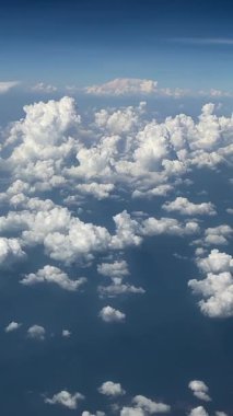 Küçük pamuk bulutlarıyla benekli kıyı okyanusu üzerinde uçak manzarası. Tatilci, güneşli suya bakıyor.