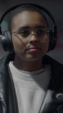 Şık kulaklıklar takan genç bir birey yoğun bir konsantrasyon ve canlı modern şehir yaşam tarzını somutlaştırıyor.