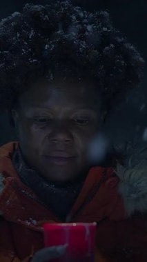 Bir insan, serin kış havasında sıcaklık uyandıran, karlı bir arazide parlayan kırmızı bir muma odaklanır.