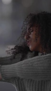 Kendine güveni tam, güzel kıvırcık saçlı bir kadın cazibesini modern bir şehir ortamında sergiliyor.