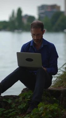 Odaklanmış ve adanmış bir birey, barışçıl sahilde bir dizüstü bilgisayar kullanıyor, işlerini doğayla güzel bir şekilde harmanlıyor.