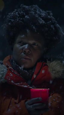 Derin düşüncelere dalmış biri, kalın giysiler içinde, dışarıda, güzel kar altında huzurlu bir anın tadını çıkarıyor.