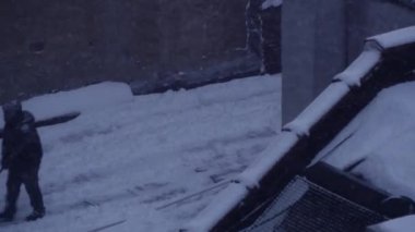 çatı katında kürekle insanlar kar