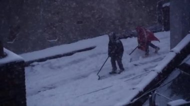 çatı katında kürekle insanlar kar