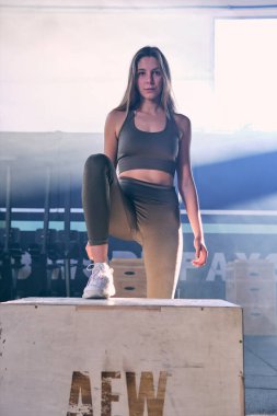 Gri arka planda, yaya geçidi tarzında atlayan formda genç kadın kutusu. Fitness, fonksiyonel, eğitim ve yaşam tarzı kavramı