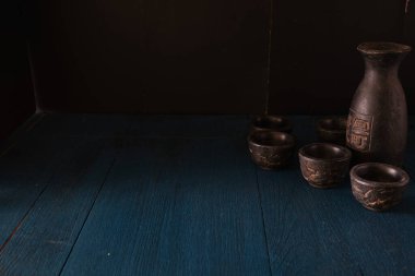 Mavi ahşap masanın üzerine koyu arkaplan şeklinde saki.