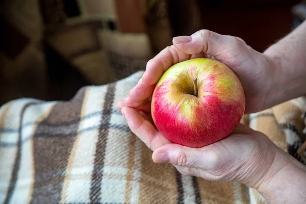 Yaşlı kadın, elmayı bir sonraki nesle hediye eder gibi tutuyor.. 