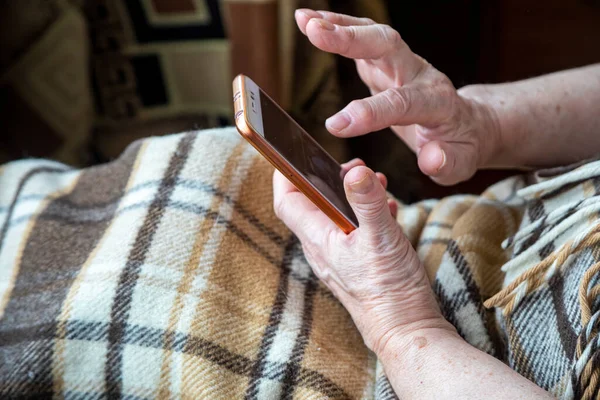 Las Manos Una Anciana Con Teléfono Móvil Llamando Para Entrega Imagen de archivo