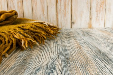 Tahta bir yüzeyde püsküllü, klasik, açık kahverengi bir ekosenin parçası.  