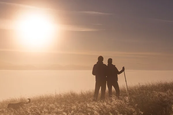 Silhouet actieve verliefde paar met Trekking paal in de ochtend mist — Stockfoto