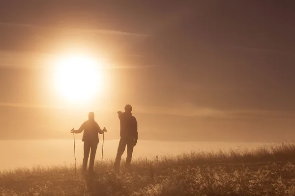 Silhouette active couple in love with Trekking pole in the morning fog — Stock Photo, Image