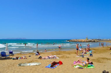 Gouves, Kıbrıs, Yunanistan - 3 Haziran 2019: Girit 'teki Gouves plajında güneşlenen turistler Yunan adalarının en büyük ve en kalabalık adaları.