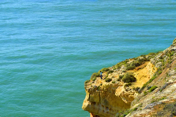 Homem pescando das formações rochosas espetaculares na costa algarvia — Fotografia de Stock