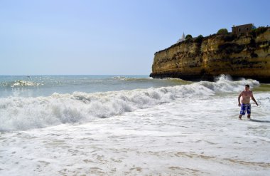 Tourist enjoying the sea on Senhora Da Rocha Beach in Portugal clipart