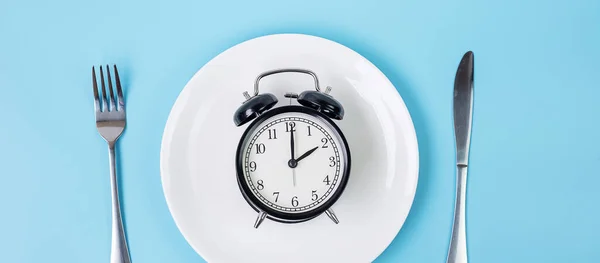 ナイフで白いプレートの上に目覚まし時計を表示し 青の背景にフォーク 断続的な断食 ケトゲンダイエット 食事計画と健康的な食品の概念 — ストック写真