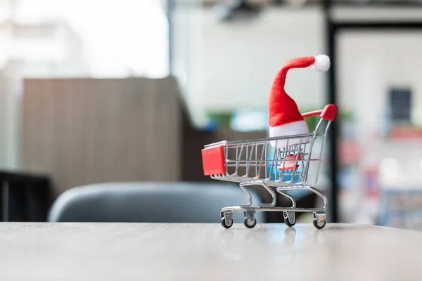 Merry Christmas with Miniature Santa Clause, Shopping cart on table at office. Holiday, Celebration, technology, e-commerce, Black Friday, Cyber Monday and online payment concept